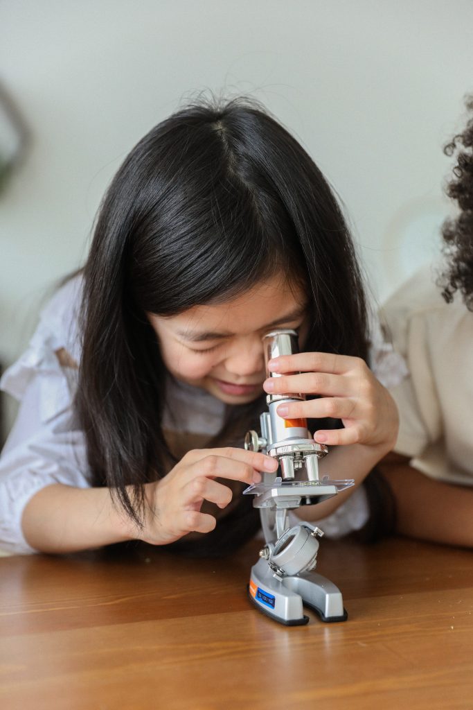 Science Courses - A girl looking through the microscope
